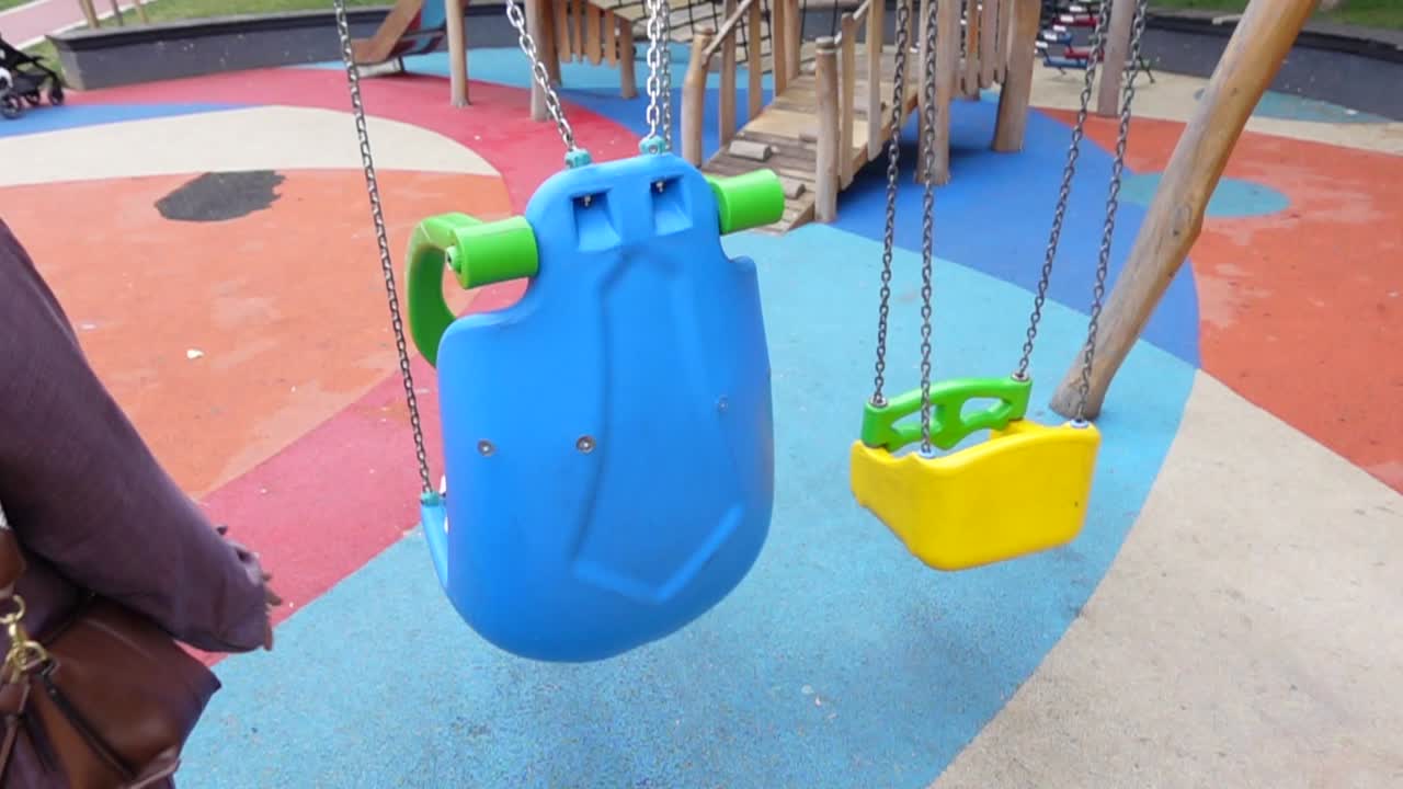 una mujer camina hacia un columpio en un patio de recreo colorido