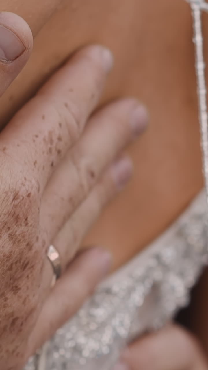 Careful guy with freckles touches back of young wife in gorgeous embroidered white lacy dress at wedding closeup slow motion. Couple at marriage celebration