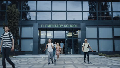 pupils leaving elementary school building. children smiling walking outside.