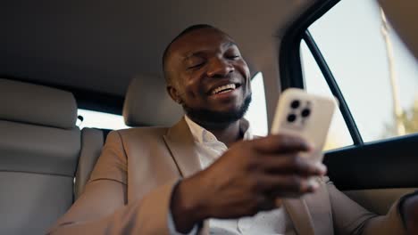 Un-Hombre-De-Negocios-Feliz-Charlando-Por-Teléfono-Y-Trabajando-Allí-Recibió-Buenas-Noticias-Sentado-Con-Un-Traje-Marrón-Y-Regocijándose-En-Un-Automóvil-Moderno.