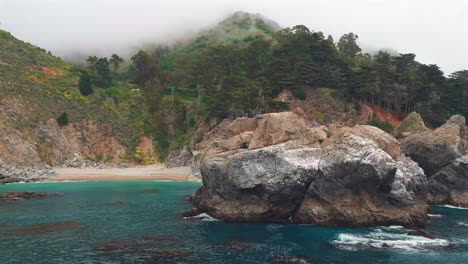 Toma-Panorámica-Desde-Detrás-De-Una-Roca-Para-Revelar-Las-Cataratas-Mcway-En-Big-Sur---Aéreo