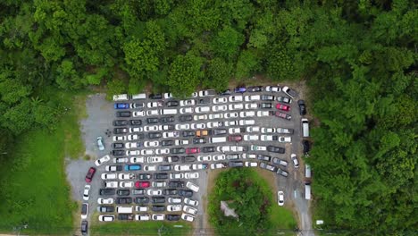 Antena:-Drone-Volando-Sobre-Un-Bolsillo-De-La-Carretera-Lleno-De-Autos-Rodeados-Por-Un-Bosque-Selvático,-Gente-Atrapada-En-La-Cola-Esperando-El-Ferry-Desde-La-Isla-De-Koh-Chang-Al-Continente,-Tailandia,-Asia