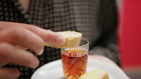 a woman hand dips biscuits into typical indian tea juice