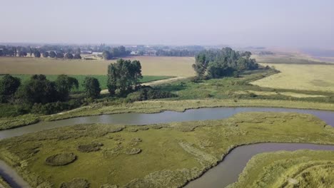 Aerial-shot-ascending-and-tilting-down-to-show-river-marshland-in-rural-United-Kingdom-on-misty-summer-evening