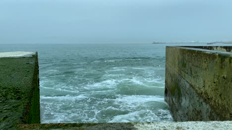 a stormy ocean water slams against a concrete breakwater - pontão da barra do douro - molhe norte, porto, portugal - slowmotion