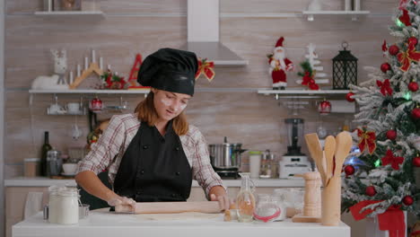 portrait of happy child wearing apron making homemade dough using rollling pin