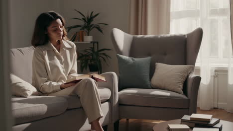 woman reading a book on a sofa in a cozy living room