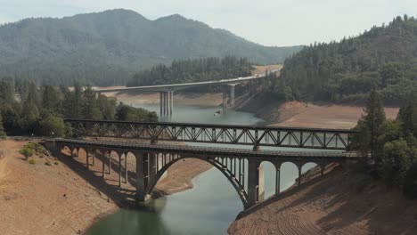 Vista-Aérea-Del-Lago-Shasta-Tiro-Ascendente-De-Vías-De-Tren-Y-Puentes-En-El-Norte-De-California-Bajos-Niveles-De-Agua-Durante-La-Sequía