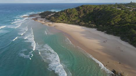 people sitting on sandy beach and admiring ocean waves in summer in point lookout - deadmans headland reserve in north stradbroke island, qld, australia