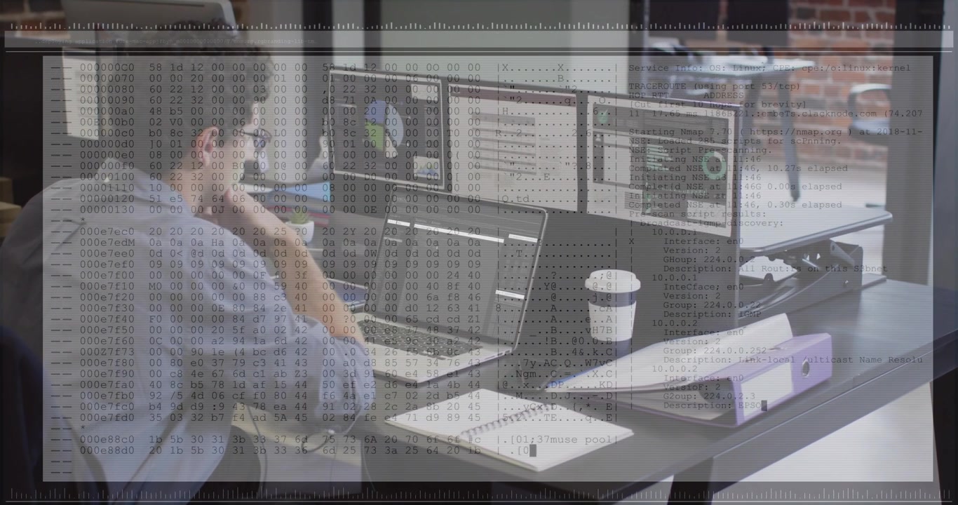 Man typing on laptop and checking monitors with charts, causing hex code overlay for tech debugging