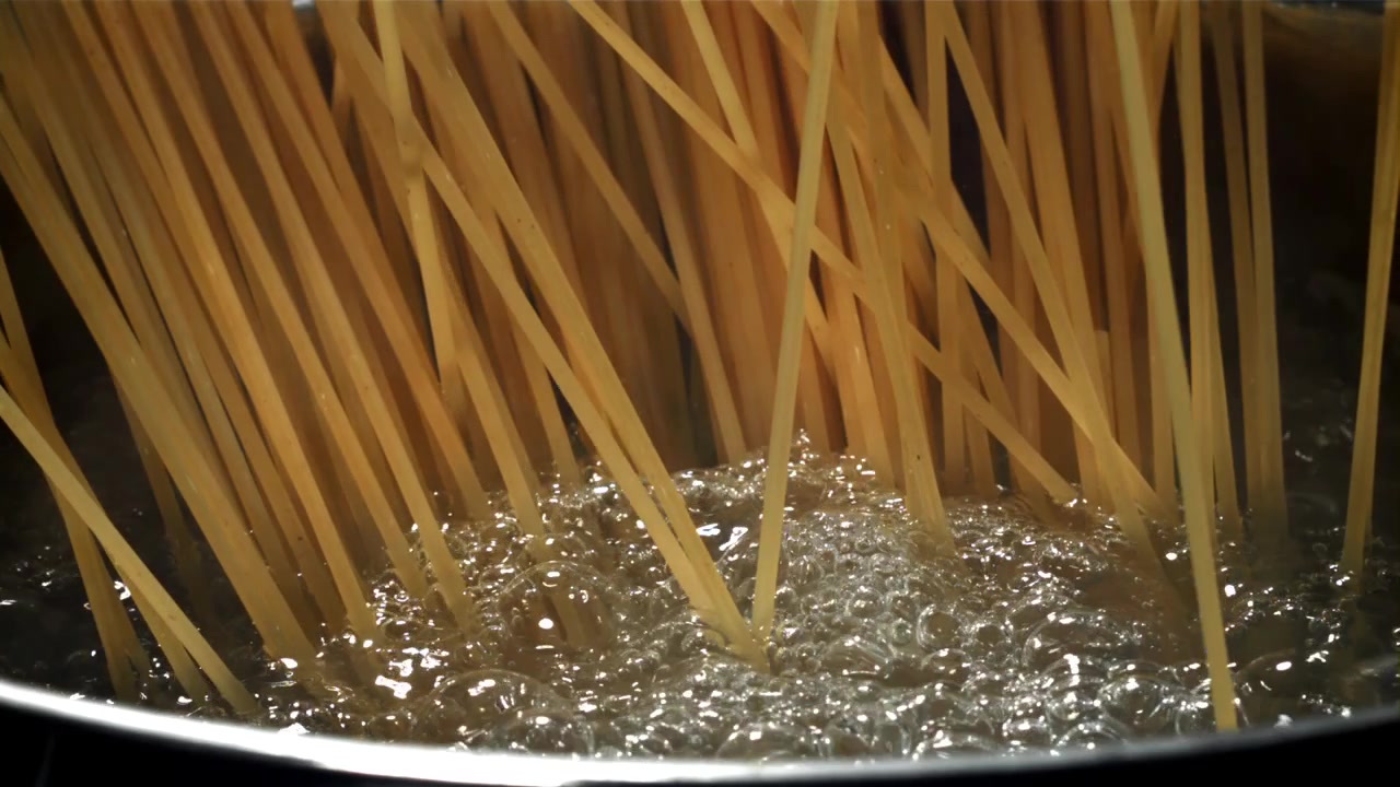 Spaghetti che cadono nell'acqua bollente in una pentola