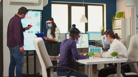 equipo multiétnico que trabaja en un proyecto financiero con máscaras de protección