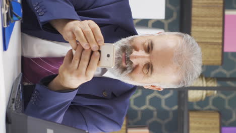video vertical de un viejo hombre de negocios enviando mensajes de texto por teléfono.