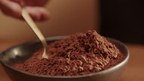 closeup shot of spoon scooping cocoa powder from bowl