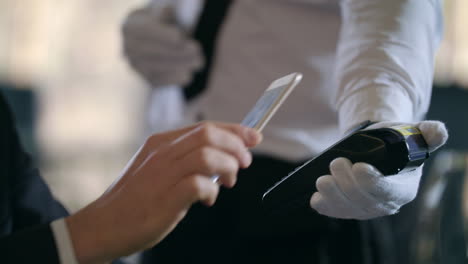 business man hand paying bill by smartphone in restaurant. contactless payment