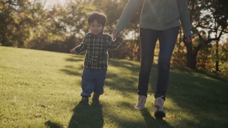 a mother with a cheerful asian baby walks in the park