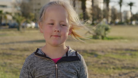 close up portrait little blonde girl looking pensive calm child enjoying peaceful summer day on urban park windy blowing hair slow motion