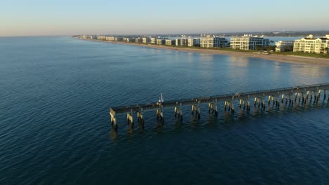 Disparo-De-Un-Dron-En-Dirección-Suroeste-Sobre-El-Muelle-Del-Lago-Worth-Florida-Hacia-La-Playa-Y-Las-Casas-Y-Condominios-Frente-Al-Mar