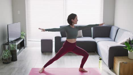 mujer caucásica manteniéndose en forma y estirándose en el tapete de yoga