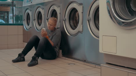 Woman-with-mobile-waiting-for-the-laundry