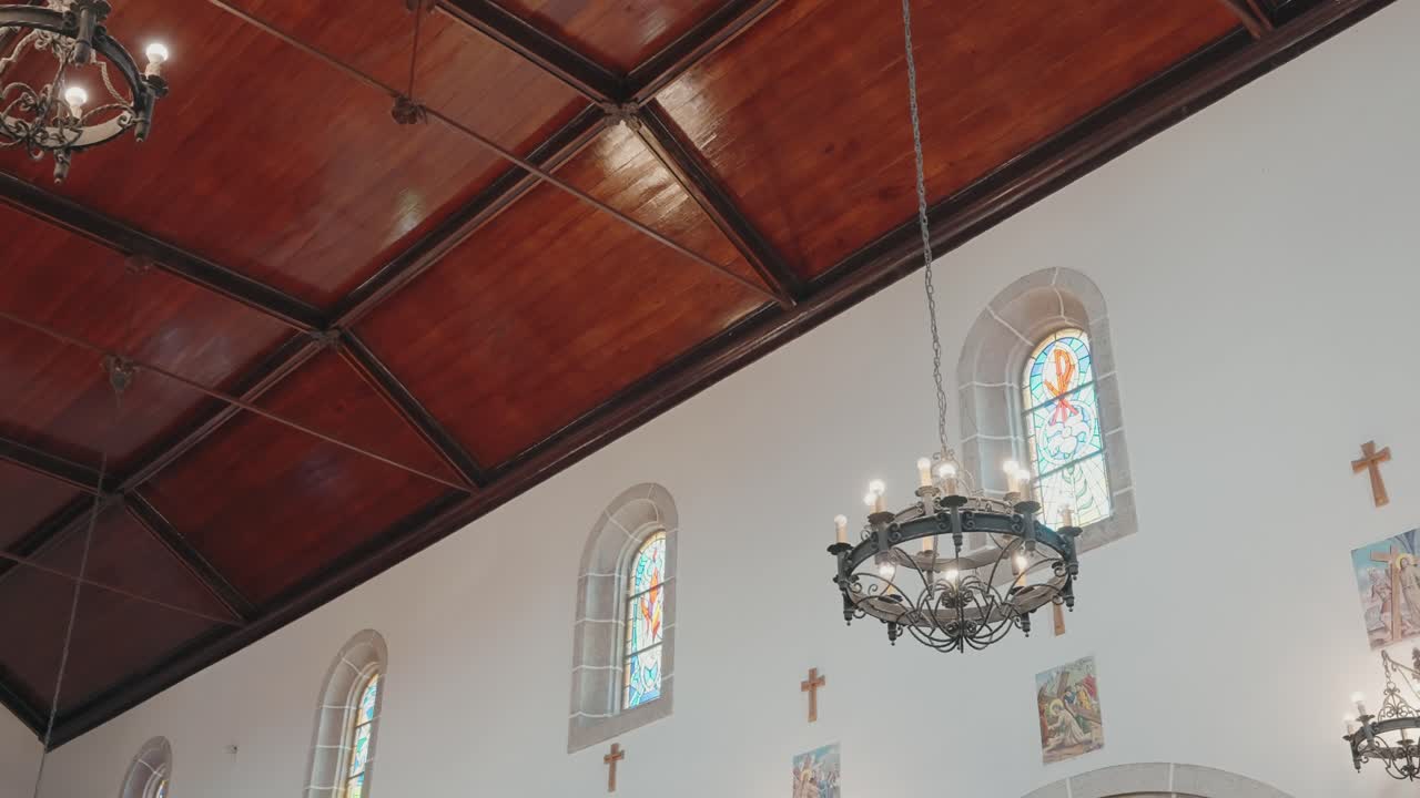 Vista dal basso verso l'alto del soffitto di una chiesa con lampadari e vetrate