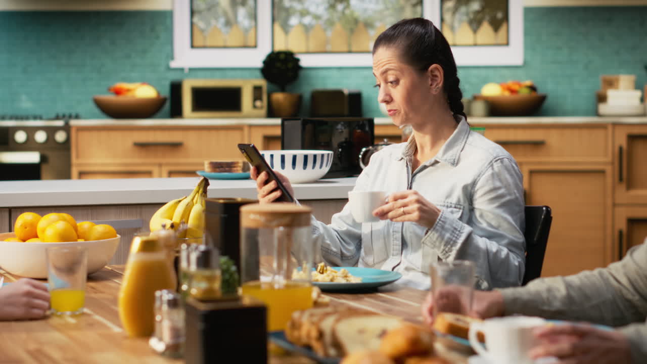 Preoccupied mother being detached and ignoring her family at the table