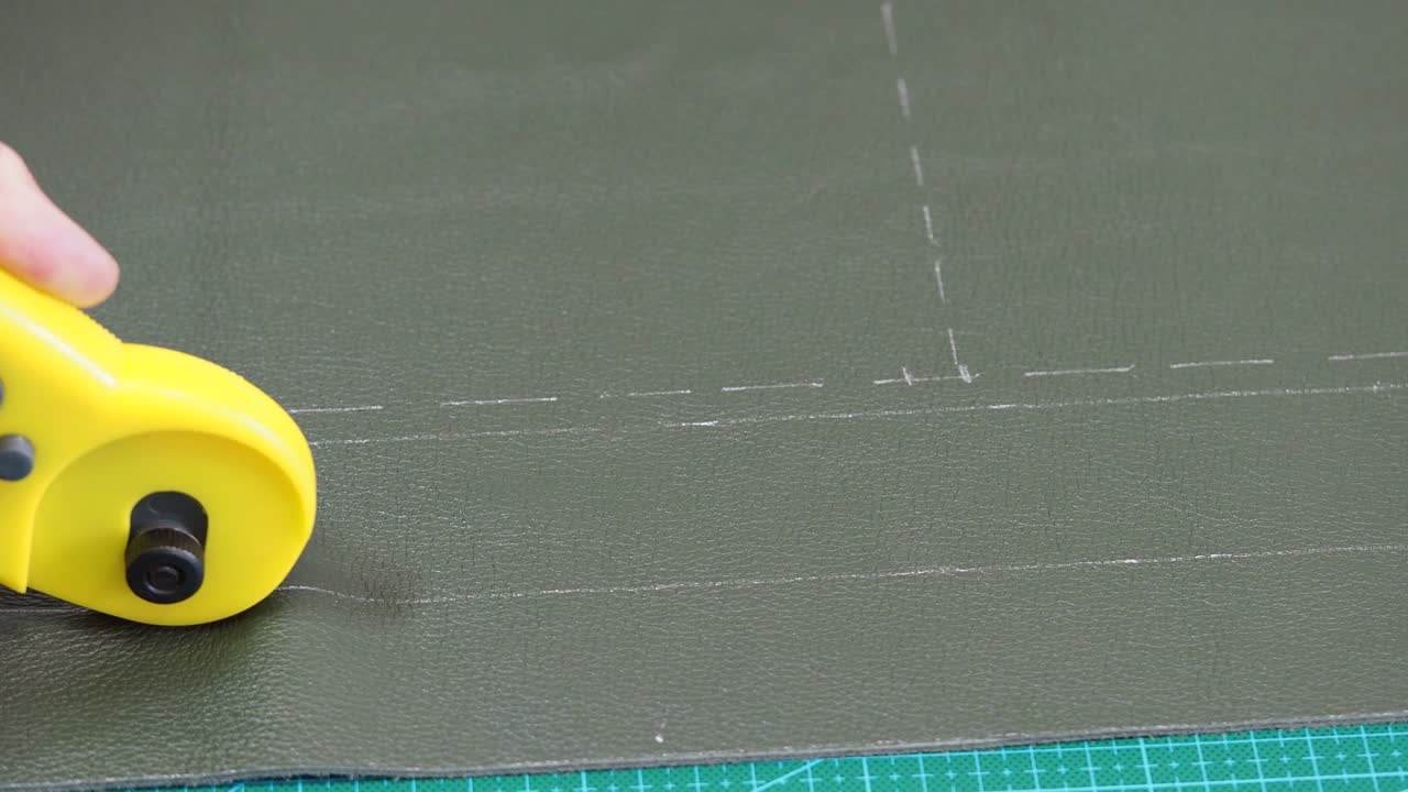 artesano corta cuero verde usando un cuchillo cortador rotativo de cerca