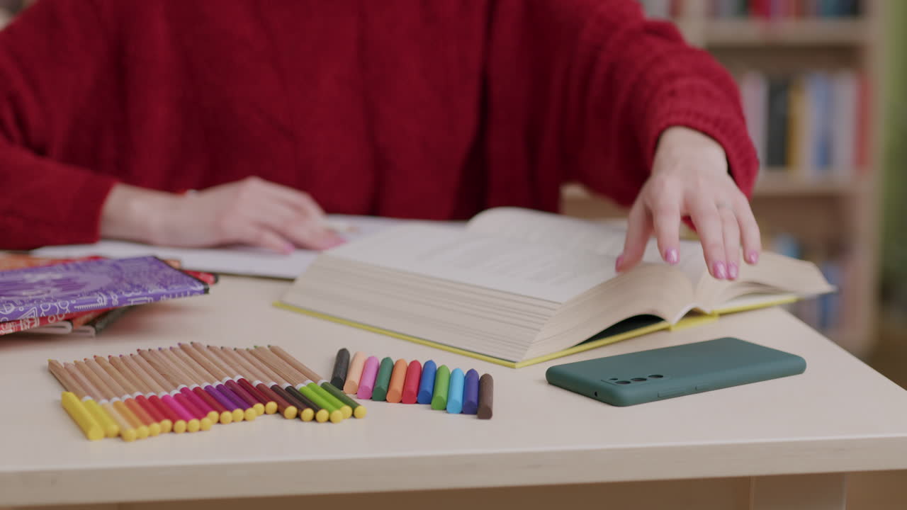 estudiante que estudia en la biblioteca distraída por la notificación en el teléfono celular