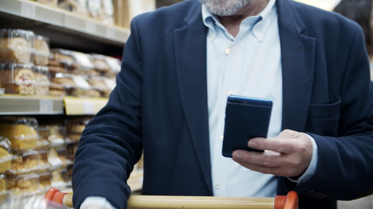Cropped shot of man using smartphone in supermarket