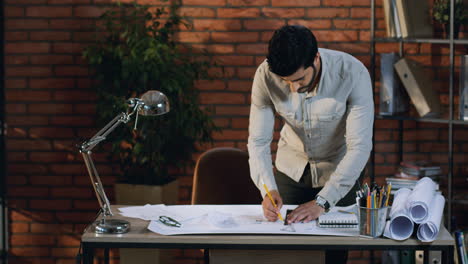 young architect drawing some plan of the new building on the big sheet of paper on desk in the urban cozy office