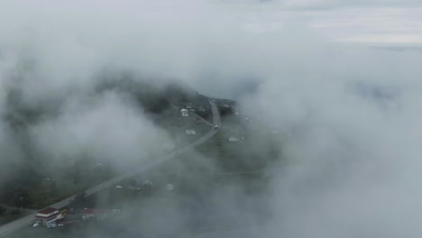 pueblo junto a la carretera en las montañas chic-choc rodeadas de nubes blancas en el río san lorenzo, península gaspe, quebec, canadá