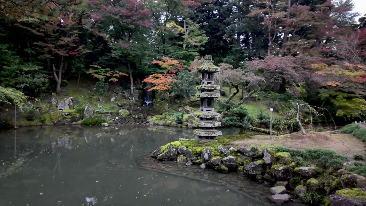 Traditional stone lantern emerging from Hisago ike Pond, surrounded by colorful autumn foliage in the serene Kenrokuen Garden