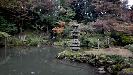traditional stone lantern emerging from hisago ike pond, surrounded by colorful autumn foliage in the serene kenrokuen garden