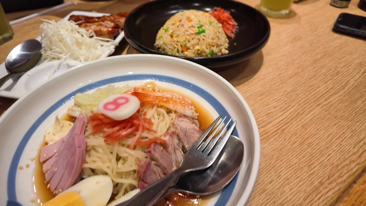 กล้องมุมสูงแพนผ่านจานข้าวผัด ไก่เทริยากิ และบะหมี่เย็นราเมน