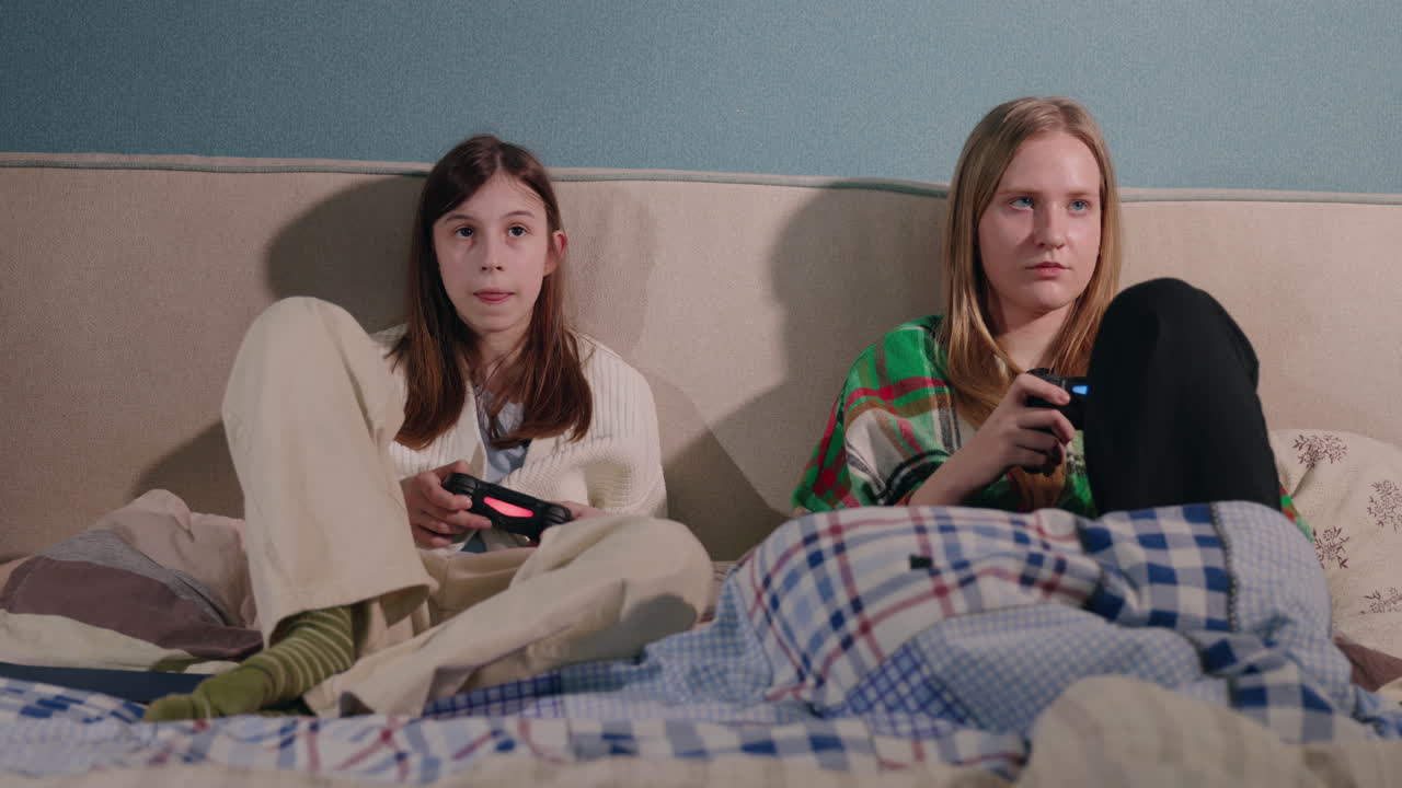 Two Teen Girls Playing Video Games on a Bed