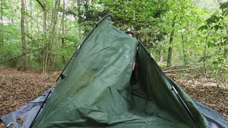person starts to build tent in forest landscape, lonely traveler in slow motion