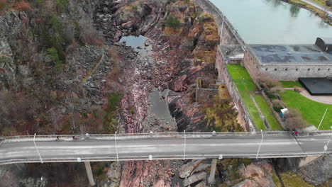 Aerial-landscape-pull-out-shot-of-a-dried-out-Trollhättan-Waterfalls-revealing-its-rocky-floor-bottom-and-rugged-cliff-in-Trollhattan-Sweden