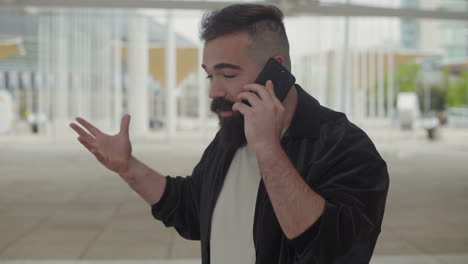 un joven emocional hablando por teléfono afuera.