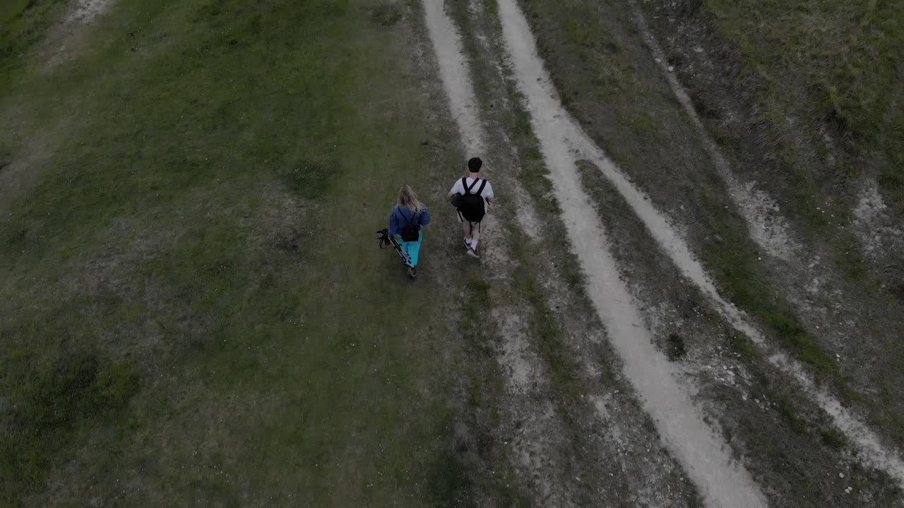 Couple walking- hiking in The Cotswolds. Drone footage following a couple of people walking on a dirt path in The Cotswolds.