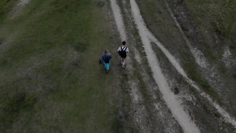 couple walking- hiking in the cotswolds. drone footage following a couple of people walking on a dirt path in the cotswolds.