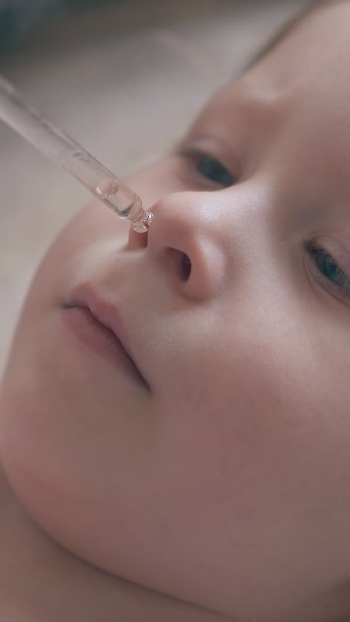 cute little girl undergoes nasal instillation procedure lying on bed in light children room extreme close view