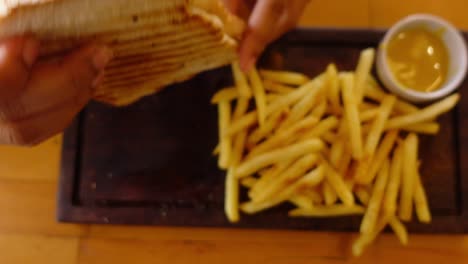 person eating a grilled cheese sandwich with french fries and mustard