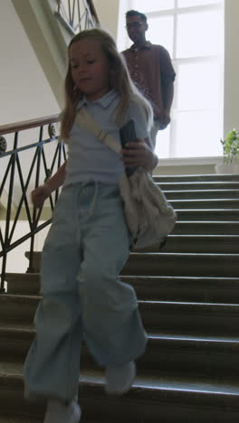 children and students running down a grand school staircase