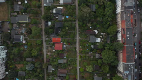 Aerial-birds-eye-overhead-top-down-panning-view-of-low-family-houses-with-gardens-among-multistorey-buildings-in-housing-estate.-Berlin,-Germany