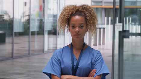 portrait of female nurse wearing scrubs standing in modern hospital building