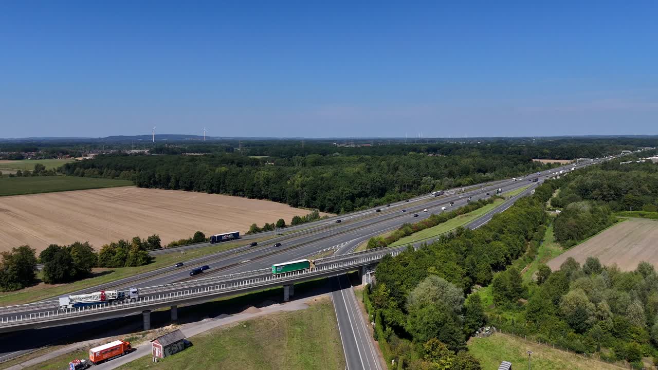 Driving trucks on ramp or German autobahn highway during sunny day. Traffic scene in agricultural countryside district in summer. Aerial wide shot. Fast freeway in Germany. Panorama