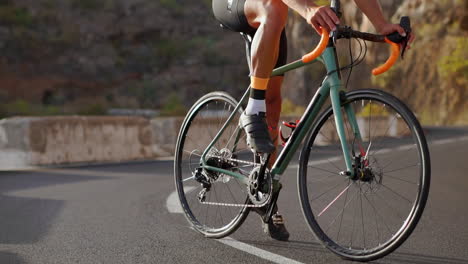 a tracking shot captures a male cyclist's journey up a mountain road. his cycling training takes place on a hilly highway road under the sun