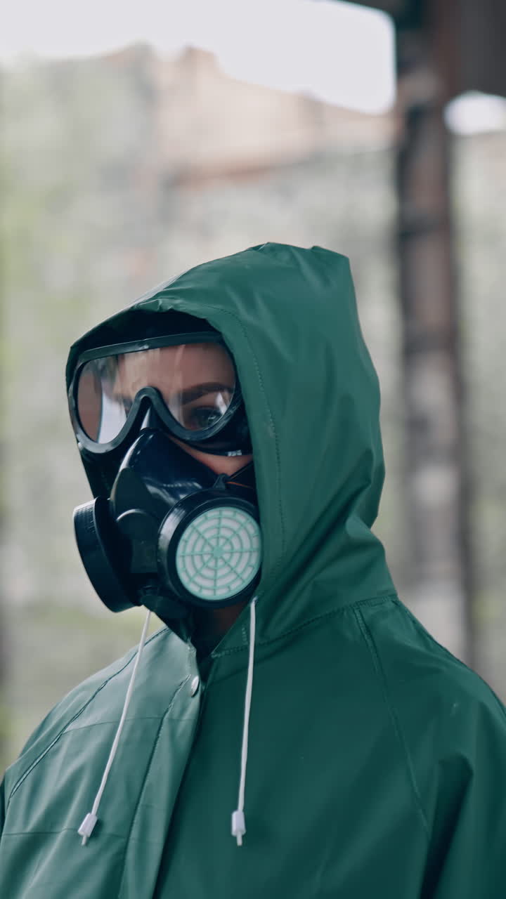 Person in chemical protective suit standing in distracted place. Survivor in abandoned place with piles of garbage from ruined buildings. Apocalypse concept. Vertical video