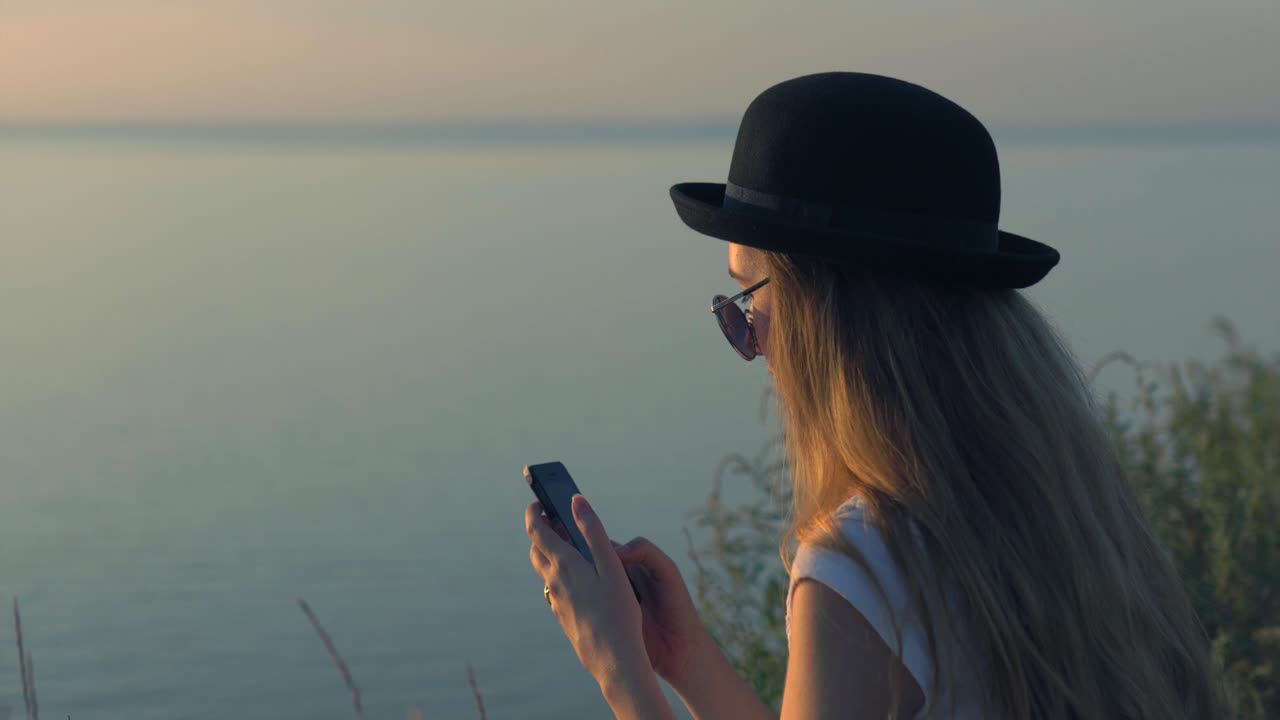 Woman using phone at sunset by the river