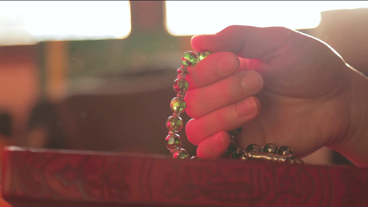 imágenes en cámara lenta de una persona orando y haciendo dhikr en una cuentas de oración
